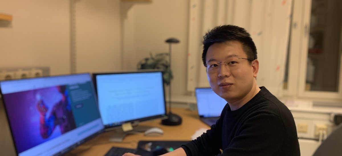 Picture of Deyou Zhang at a desk with computer screens